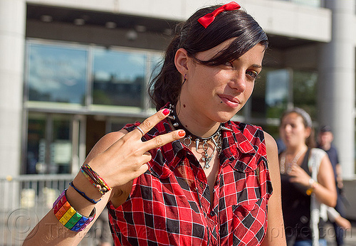 pretty woman in red checkered outfit, bowtie hairclip, bracelets, checkered shirt, gay pride, peace sign, rainbow bracelet, red shirt, spiky necklace, v sign, victory sign, woman