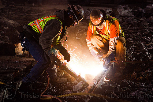 railroad workers cutting a track rail with a oxy-acetylene torch, dust mask, high-visibility jacket, high-visibility vest, light rail, man, muni, night, ntk, oxy-acetylene cutting torch, oxy-fuel cutting, railroad construction, railroad tracks, railway tracks, reflective jacket, reflective vest, safety glasses, safety gloves, safety helmet, safety vest, san francisco municipal railway, sparks, track maintenance, track work, welder, worker, working