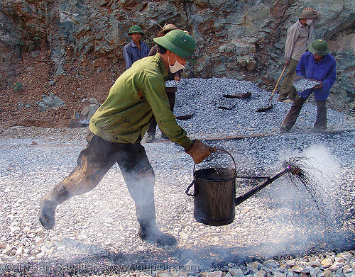 road paving - spraying hot asphalt over gravel with watering can - vietnam, face mask, gravel, groundwork, hot asphalt, hot bitumen, men, pavement, paving, road construction, roadworks, smoke, smoking, spraying, watering can, workers, working