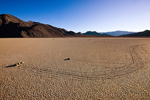 sailing stones travelling together on the racetrack - death valley, cracked mud, death valley, dry lake, dry mud, mountains, racetrack playa, sailing stones, sliding rocks