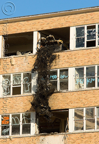 skid steer loader throwing debris from window - building demolition, abandoned building, abandoned hospital, building demolition, debris, front loader, presidio hospital, presidio landmark apartments, skid steer loader, windows