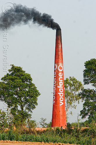 smokestack with vodafone advertising - black smoke - air pollution, ad, advertising, air pollution, brick kiln, carbon footprint, cellphone, environment, global warming, kashmir, rural, smoke, smokestack, trees, vodafone