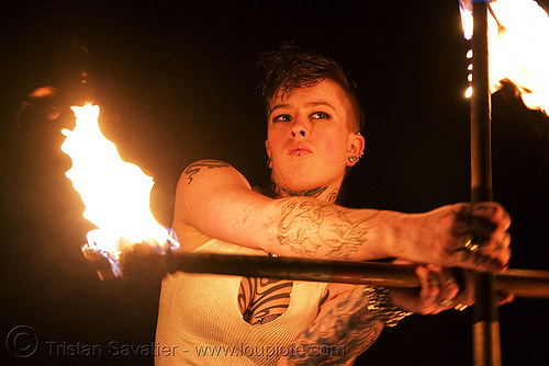 spinning fire staffs (san francisco) - fire dancer - leah, cross, double staff, fire dancer, fire dancing, fire performer, fire spinning, fire staffs, fire staves, leah, night, spinning fire, tattooed, tattoos, woman