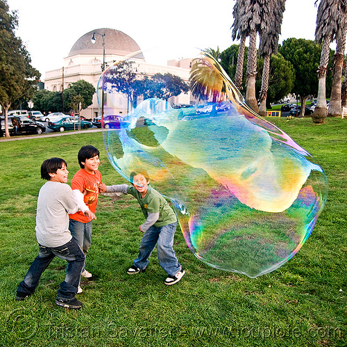 three kids and a giant soap bubble, big bubble, children, giant bubble, iridescent, kids, lawn, park, playing, soap bubbles
