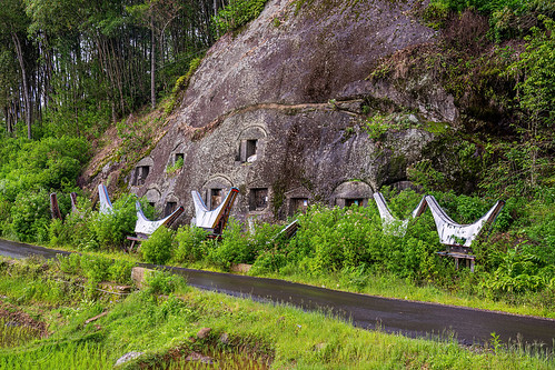 toraja rock-tombs in rock wall, burial site, cemetery, cllff, graves, graveyard, liang pak, miniature tongkonan, road, rock tombs, tana toraja, tongkonan roof