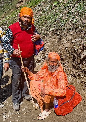 two hindu pilgrims resting on trail - amarnath yatra (pilgrimage) - kashmir, amarnath yatra, beard, bhagwa, hiking cane, hindu pilgrimage, hinduism, kashmir, man, mountain trail, mountains, pilgrim, resting, saffron color, walking stick