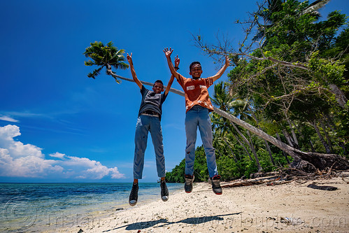 two indonesian boys jumping on the beach, sulawesi