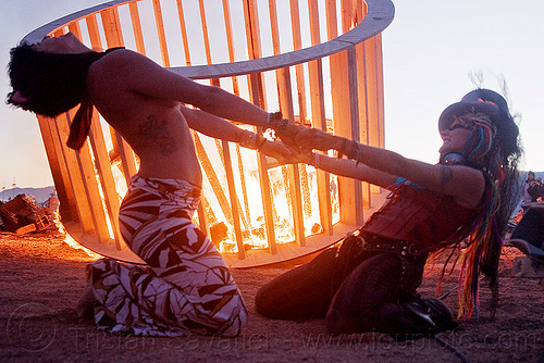 two women dancing - cylindrical wooden frame burning, burning, cylinder, cylindrical, dancing, dusk, fire, frame, heather, stretching, woman, wood, wooden
