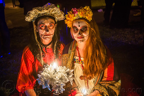 two women with sugar skull makeup - dia de los muertos (san francisco), candle, day of the dead, dia de los muertos, face painting, facepaint, flower headdress, halloween, night, sugar skull makeup, white flowers, women