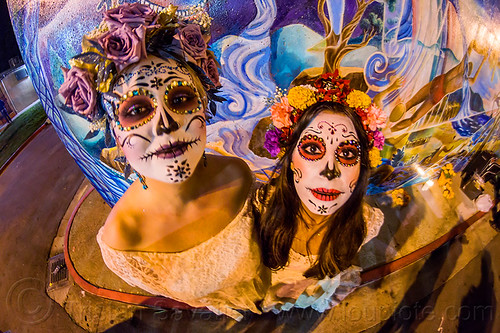 two women with white sugar skull makeup and flower headdresses, andrea, bindis, day of the dead, dia de los muertos, face painting, facepaint, flower headdress, flowers, halloween, mariana, mural, night, sugar skull makeup, women