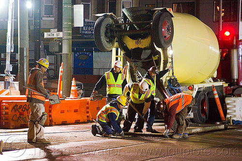 using a screed board to flatten the concrete, cement truck, concrete truck, helmet, high-visibility jacket, high-visibility vest, light rail, men, muni, night, ntk, railroad construction, railroad tracks, railway tracks, reflective jacket, reflective vest, safety vest, san francisco municipal railway, screed board, track maintenance, track work, wet concrete, workers