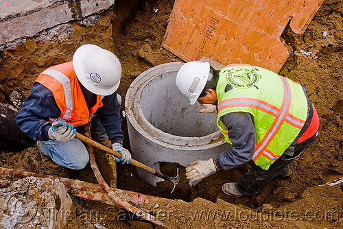 utility workers digging around storm drain construction, comcrete, construction workers, drainage, high-visibility jacket, high-visibility vest, reflective jacket, reflective vest, safety helmet, safety jacket, storm drain, utility workers, working
