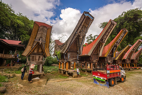 village street with toraja rice granaries with traditional tongkonan horn-shape roofs, alang, rice granaries, rice-barns, tana toraja, tongkonan house, tongkonan roof, truck, village