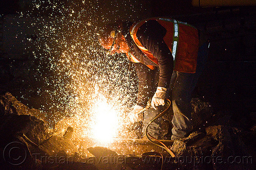 welder cutting a track rail with a oxy-acetylene torch, high-visibility jacket, high-visibility vest, light rail, man, muni, night, ntk, oxy-acetylene cutting torch, oxy-fuel cutting, railroad construction, railroad tracks, railway tracks, reflective jacket, reflective vest, safety glasses, safety gloves, safety helmet, safety vest, san francisco municipal railway, sparks, track maintenance, track work, welder, worker, working