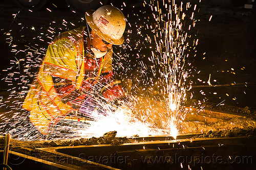 welder cutting a track rail with a oxy-acetylene torch, high-visibility jacket, high-visibility vest, light rail, man, muni, night, ntk, oxy-acetylene cutting torch, oxy-fuel cutting, railroad construction, railroad tracks, railway tracks, reflective jacket, reflective vest, safety glasses, safety helmet, safety vest, san francisco municipal railway, sparks, track maintenance, track work, welder, worker, working