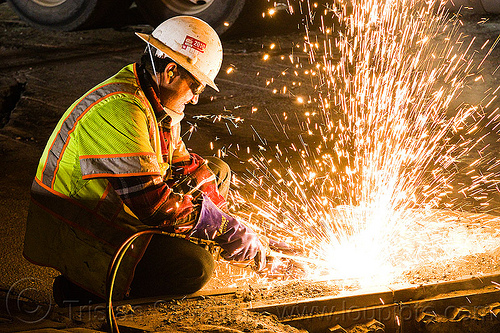 welder cutting rail with oxy-acetylene torch, high-visibility jacket, high-visibility vest, light rail, man, muni, night, ntk, oxy-acetylene cutting torch, oxy-fuel cutting, railroad construction, railroad tracks, railway tracks, reflective jacket, reflective vest, safety glasses, safety gloves, safety helmet, safety vest, san francisco municipal railway, sparks, track maintenance, track work, welder, worker