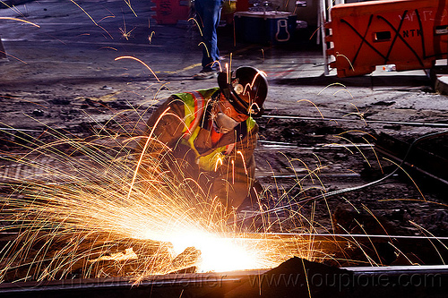 welder cutting rail with oxy-acetylene torch, demolition, high-visibility jacket, high-visibility vest, light rail, man, muni, night, ntk, oxy-acetylene cutting torch, oxy-fuel cutting, railroad construction, railroad tracks, railway tracks, reflective jacket, reflective vest, safety helmet, safety vest, san francisco municipal railway, track maintenance, track work, welder, welding, worker, working