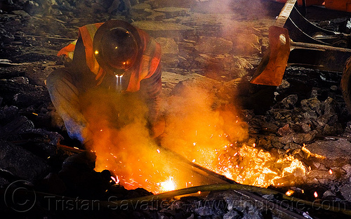 welder cutting rail with torch, high-visibility jacket, high-visibility vest, light rail, man, muni, night, ntk, oxy-acetylene cutting torch, oxy-fuel cutting, railroad construction, railroad tracks, railway tracks, reflective jacket, reflective vest, safety glasses, safety helmet, safety vest, san francisco municipal railway, track maintenance, track work, welder, worker, working