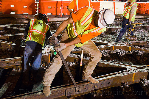 worker unscrewing rail fish plate - - muni railway construction site (san francisco), bolting, bolts, diamond crossing, fish plate, high-visibility jacket, high-visibility vest, light rail, man, muni, ntk, railroad construction, railroad tracks, railway tracks, reflective jacket, reflective vest, safety helmet, safety vest, san francisco municipal railway, screwing, screws, track maintenance, track work, worker, working, wrench