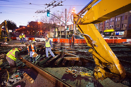 workers examining new track rail, diamond crossing, high-visibility jacket, high-visibility vest, hydraulic arm, light rail, men, muni, ntk, overhead lines, railroad construction, railroad tracks, railway tracks, reflective jacket, reflective vest, safety helmet, safety vest, san francisco municipal railway, track maintenance, track work, workers, working