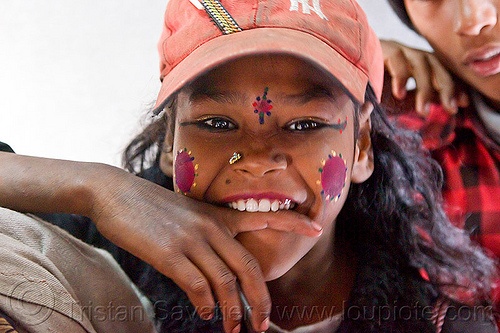 young girl biting finger (india), biting finger, cap, circus performer, contortionist, face paint, girl, hat, itinerant circus, makeup, nose piercing, nostril piercing, shiny eyes, tilak, tilaka