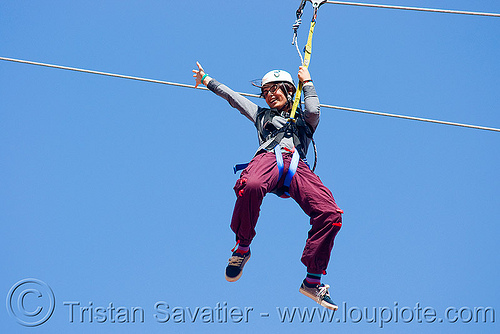 zoey riding the zip-line over san francisco, adventure, blue sky, cable line, cables, climbing helmet, embarcadero, hanging, mountaineering, moving fast, speed, steel cable, trolley, tyrolienne, urban, woman, zip line, zip wire