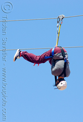 zoey riding the zip-line over san francisco, adventure, blue sky, cable line, cables, climbing helmet, embarcadero, hanging, mountaineering, moving fast, speed, steel cable, trolley, tyrolienne, upside-down, urban, woman, zip line, zip wire