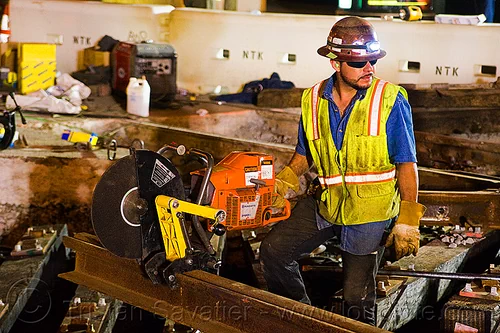 abrasive cut-off saw attached to track rail, 3120x, abrasive saw, cut-off saw, cutting, high-visibility jacket, high-visibility vest, huskvama, light rail, man, muni, ntk, power tool, railroad construction, railroad tracks, railway tracks, reflective jacket, reflective vest, safety helmet, safety vest, san francisco municipal railway, sparks, track maintenance, track work, worker, working