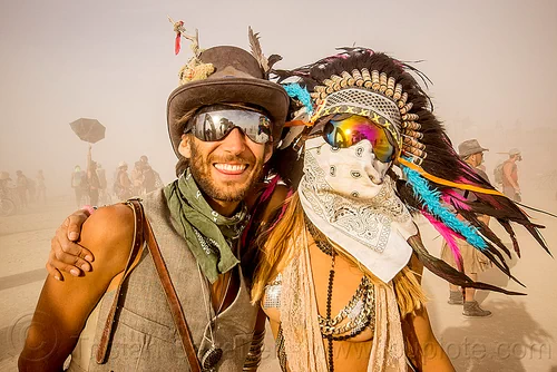 burning man - couple during white out, attire, bandana, burning man outfit, dust storm, face mask, feather headdress, feathers, mathieu, mirror sunglasses, pia, white out, windy, woman