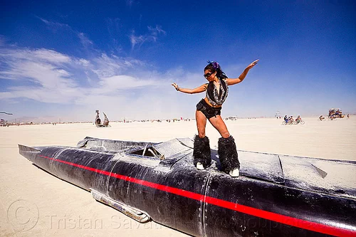 burning man - woman dancing on rocket car, art car, black leg warmers, burning man art cars, dancing, furry leg warmers, long, mutant vehicles, rocket car, woman