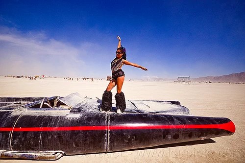 burning man - woman dancing on the rocket car, art car, black leg warmers, burning man art cars, dancing, furry leg warmers, long, mutant vehicles, necklaces, rocket car, woman