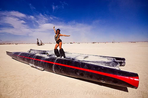 burning man - woman dancing on the rocket car, art car, black leg warmers, burning man art cars, dancing, furry leg warmers, long, mutant vehicles, necklaces, rocket car, woman
