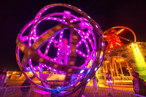 burning man - woman inside giant animated steel rings sculpture, animated, art installation, burning man at night, disc-go-sphere, glowing, led light, sculpture, the man, woman