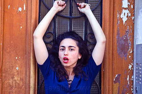 italian girl with arms raised, brunette, curly hair, dilve, hands, house door, ironwork, italian woman, long hair, red lipstick