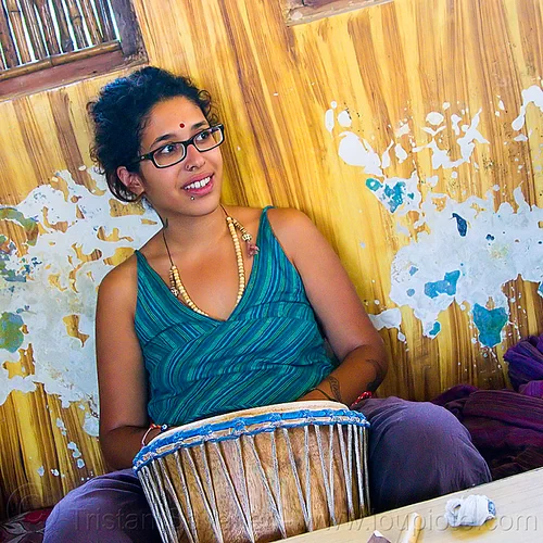 maryam with djembe drum, bindi, bracelets, djembe drum, drummer, eyeglasses, eyewear, lip piercing, maryam, musical instrument, necklaces, peeling paint, percussion, prescription glasses, rishikesh, sitting, spectacles, woman