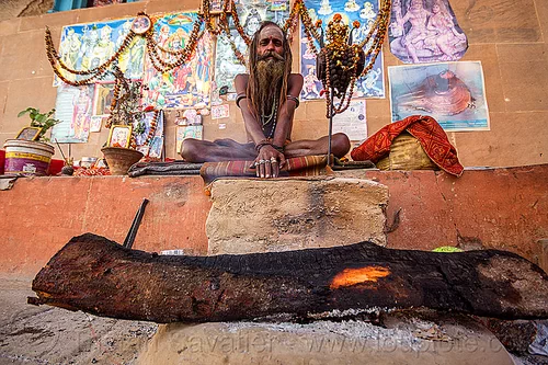 naga sadhu and his camp fire in varanasi (india), baba, beard, campfire, cross-legged, damaru drum, dreadlocks, ghats, hindu ritual drum, hinduism, man, naga babas, naga sadhus, posters, sadhu, sitting, tree log, varanasi, wood