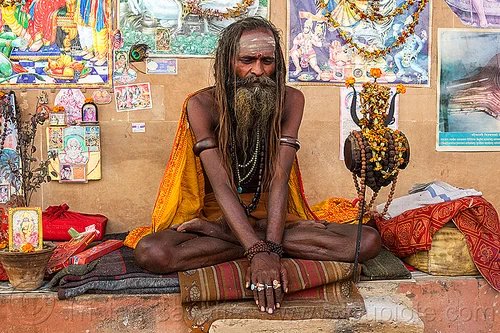 naked baba - naga sadhu sitting crosslegged in varanasi (india), baba, beard, bracelets, cross-legged, damaru drum, dreadlocks, finger rings, ghats, hindu man, hindu ritual drum, hinduism, naga babas, naga sadhus, necklaces, posters, sadhu, sitting, tilak, tilaka, trident, varanasi