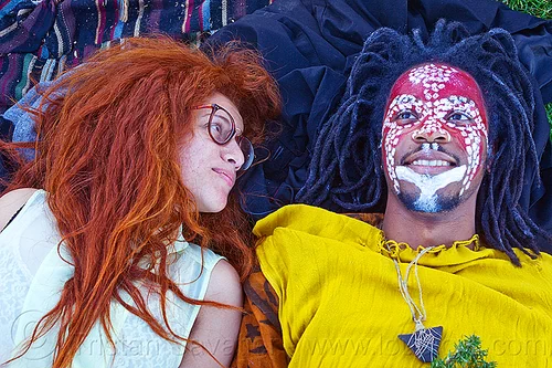 redhead & dreadlocks - couple in dolores park (san francisco), african american man, african face paint, black man, curly hair, dreadlocks, eyeglasses, eyewear, face painting, facepaint, glasses, jason, laying down, long hair, lulu, makeup, red, redhead, spectacles, stone necklace, triangular necklace, tribal face paint, white, woman, yellow tunic