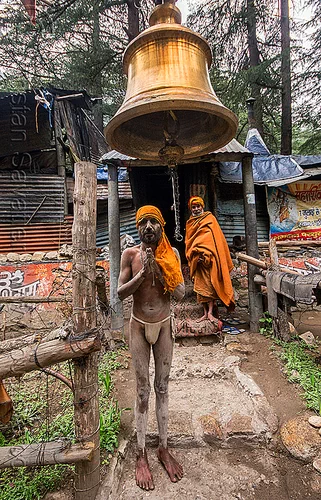 sadhu under large brass bell (india), baba, bell, bhagirathi valley, bhagwa, brass, hindu, hinduism, holy ash, men, naga babas, naga sadhus, sacred ash, sadhu, saffron color, test1, vibhuti