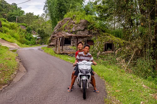 toraja kids on motorbike, with rock tombs in the back, burial site, cemetery, graves, graveyard, kids, kig, liang pak, motorcycle, road, rock tombs, tana toraja