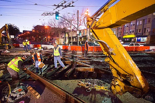 workers examining new track rail, diamond crossing, high-visibility jacket, high-visibility vest, hydraulic arm, light rail, men, muni, ntk, overhead lines, railroad construction, railroad tracks, railway tracks, reflective jacket, reflective vest, safety helmet, safety vest, san francisco municipal railway, track maintenance, track work, workers, working