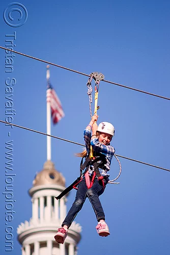zip-line over san francisco, adventure, american flag, blue sky, cable line, cables, campanil, child, climbing helmet, clock tower, embarcadero tower, ferry building, hanging, kid, mountaineering, moving fast, speed, steel cable, trolley, tyrolienne, urban, us flag, zip line, zip wire